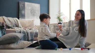 母亲带着一个孩子在他的房子的白色内部被打开，油漆罐坐在地板上，蘸着你的水